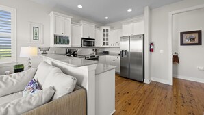 A modern kitchen with white cabinetry, stainless steel appliances, and a wooden floor. - Townhome with stunning view of Matlacha Pass (Matlacha)
