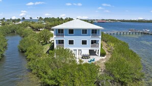 A two-story house with a balcony, surrounded by water and vegetation. - Townhome with stunning view of Matlacha Pass (Matlacha)
