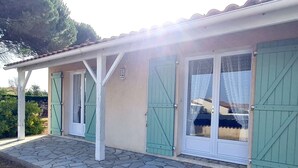 Un bâtiment doté d’un patio carrelé, de volets verts et d’un sol en pierre.