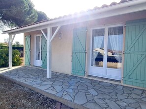 Un bâtiment doté d’un patio carrelé, de volets verts et d’un sol en pierre.