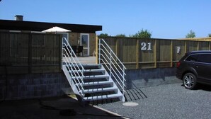A parking area with a staircase leading to a building entrance. - Plesners Anneks (Skagen)