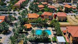 An aerial view of a resort with multiple buildings, palm trees, and a swimming pool. - Modern 2-Bedroom Home with Pools in Noord (Noord)