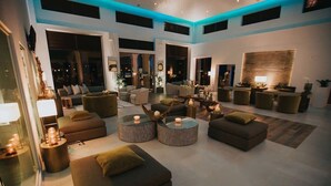 A spacious living area with sofas, round coffee tables, and a dining area with chairs. - Modern 2-Bedroom Home with Pools in Noord (Noord)