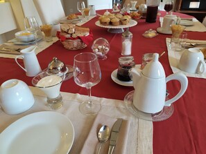 Una escena de desayuno con platos blancos, tazas y un mantel rojo.