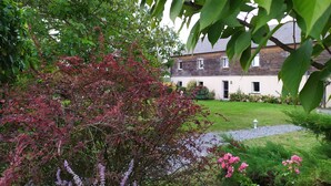Una casa con jardín, un camino de grava y césped.