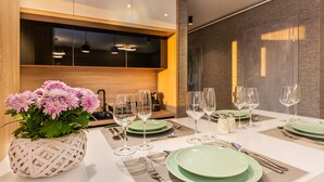 A dining table set with green plates, wine glasses, and cutlery, with a woven basket of flowers on the left. - Promenada Studios (Brasov)