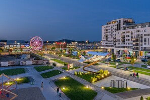 A modern urban area with a Ferris wheel, a shopping center, and a multi-story building with balconies. - Promenada Studios (Brasov)