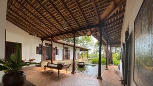 An open-air covered patio with a tiled floor, wooden benches, and a potted plant.