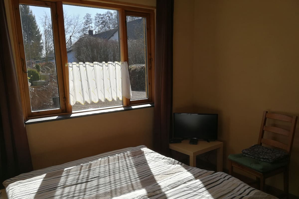 Une chambre à coucher avec un lit, un téléviseur posé sur une petite table et une chaise.