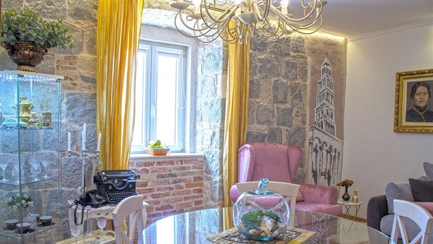 A cozy living room with a stone wall, a glass table, and a pink armchair. - Split Theatre Apartments (Split)