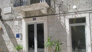 A building with a stone facade, two potted plants in front, and a sign above the entrance. - Split Theatre Apartments (Split)