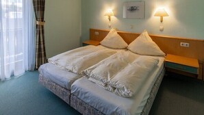 A hotel room with a large bed, two bedside tables, a headboard, and a window with curtains. - Gasthof Frank (Heroldsbach)