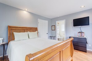 Un dormitorio con una cama de madera, un aparador, un televisor y una mesita.