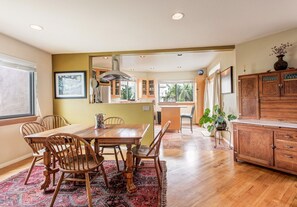A spacious kitchen with wooden cabinets, a dining table with chairs, and a large window providing natural light.
