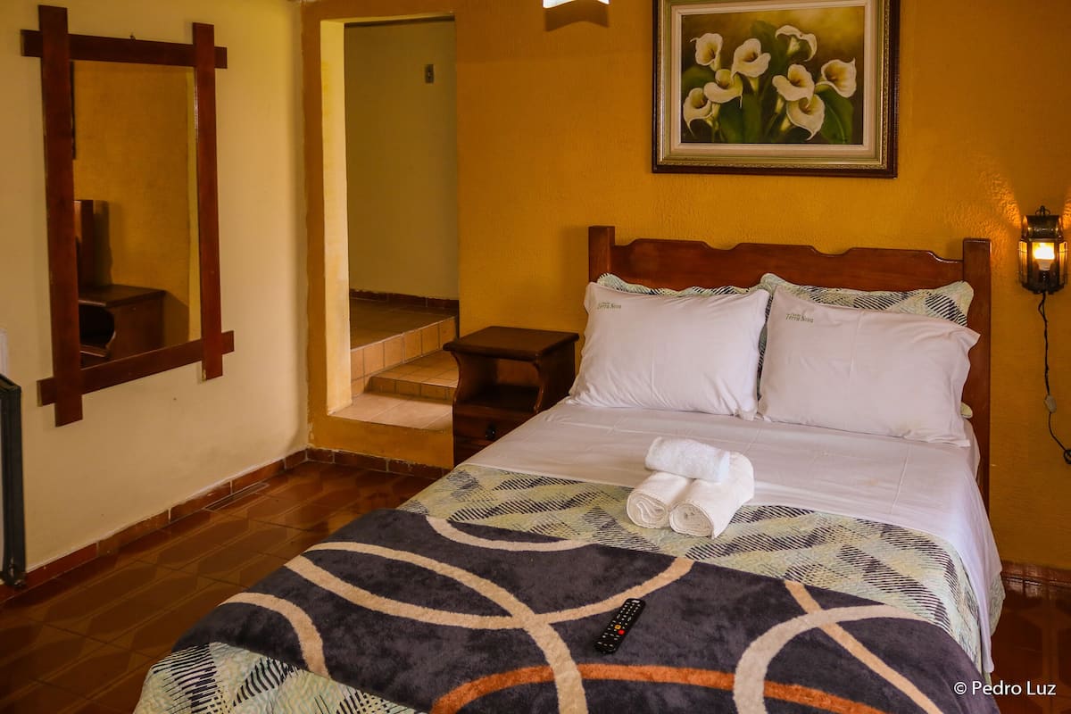 Ein Hotelzimmer mit Bett, Nachttisch, einem Gemälde an der Wand und einer Treppe, die in einen anderen Raum führt.