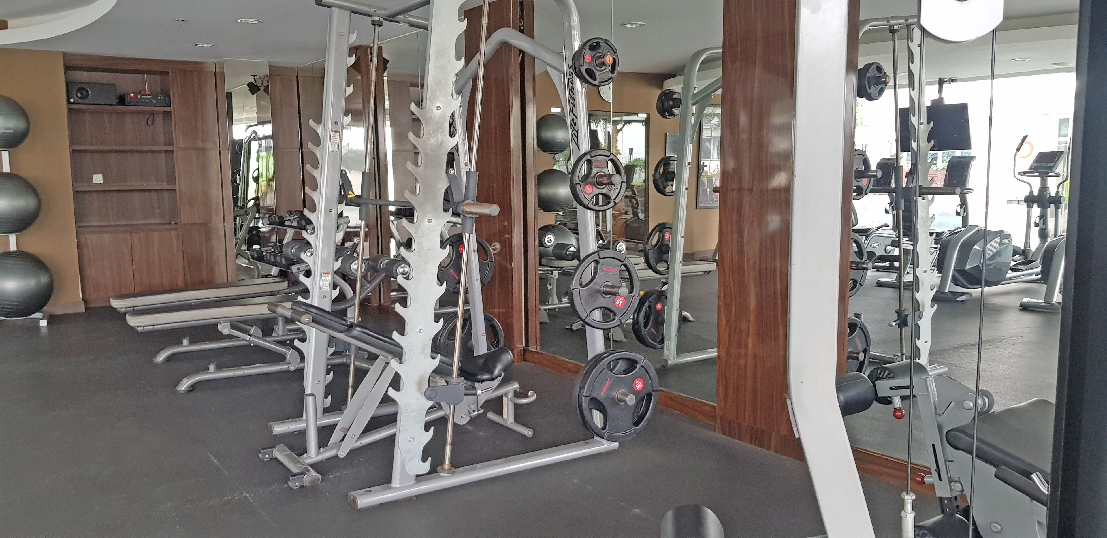 Una palestra con diverse attrezzature per l'allenamento, tra cui macchinari per pesi, pesi liberi e macchinari cardio.