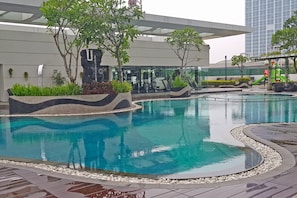 A swimming pool with a wavy edge design, surrounded by a pebble border. - Apatel U Residence Tower 2 (Curug)