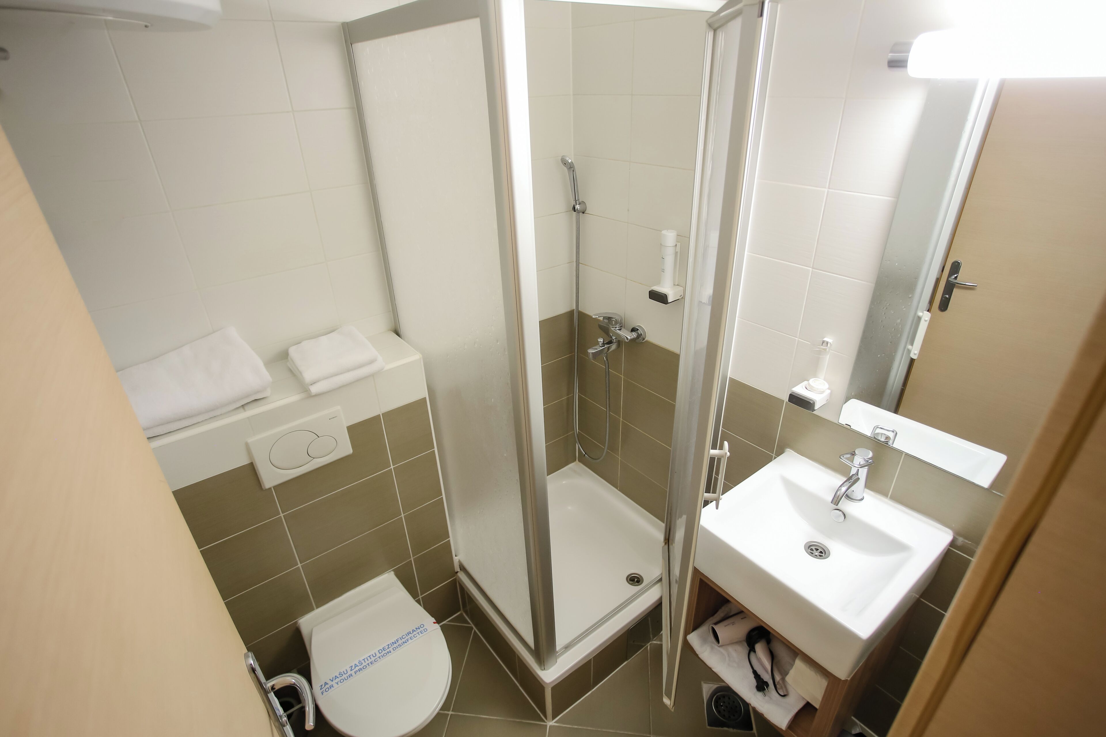 A bathroom with a shower, toilet, sink, and towel rack.