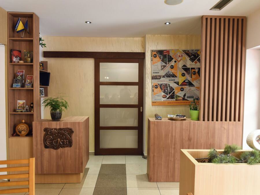 A reception desk with a wooden finish, a plant on top, and a bulletin board with various notices.