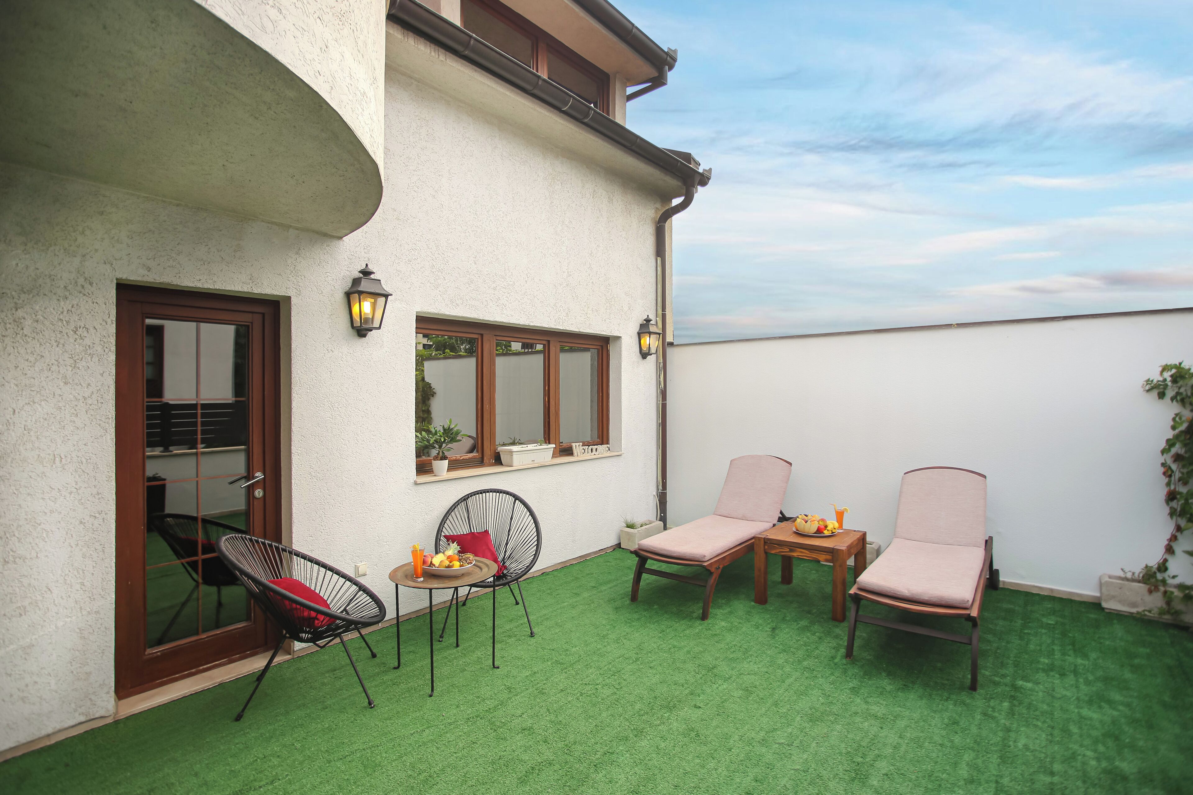 Une terrasse avec deux chaises, une table et un pot de fleurs.