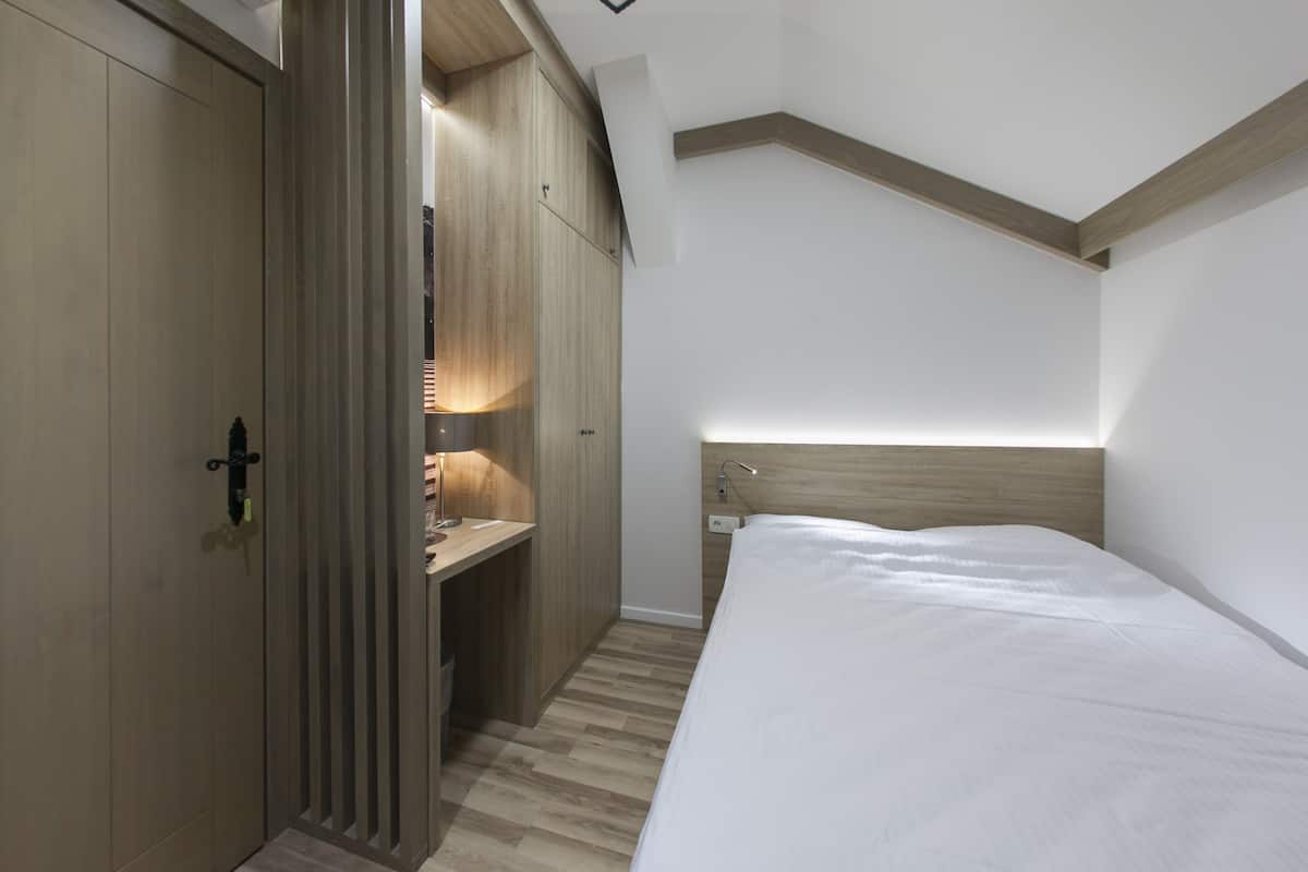 Un dormitorio con un armario de madera, una mesita de noche y una cama.