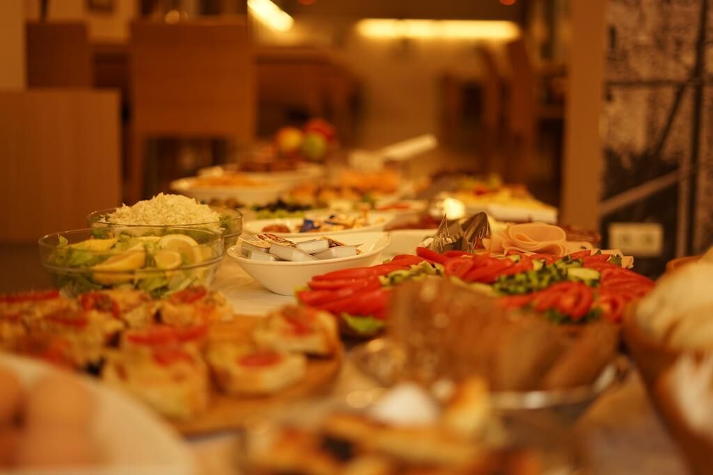 A buffet table with various dishes, including salads, vegetables, and bread.