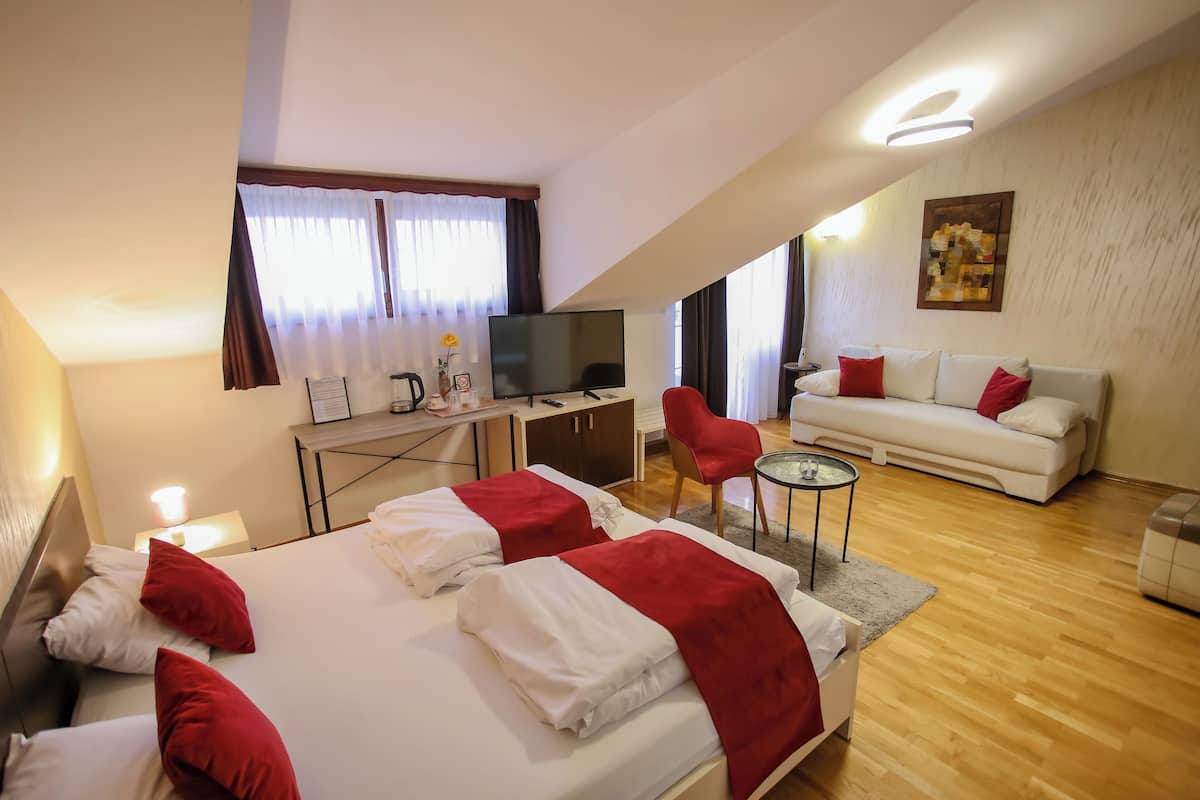 Una habitación de hotel con cama, televisión, sofá y escritorio.