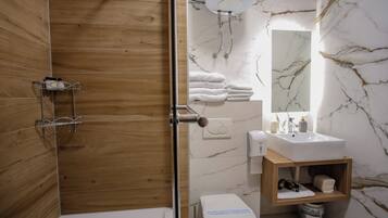 A modern bathroom with a wooden shower enclosure, a white sink with a marble backsplash, and a wooden vanity with a mirror.