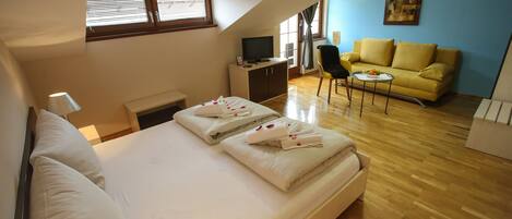 Un dormitorio con una cama, un televisor sobre un mueble, un sofá y un cuadro en la pared.