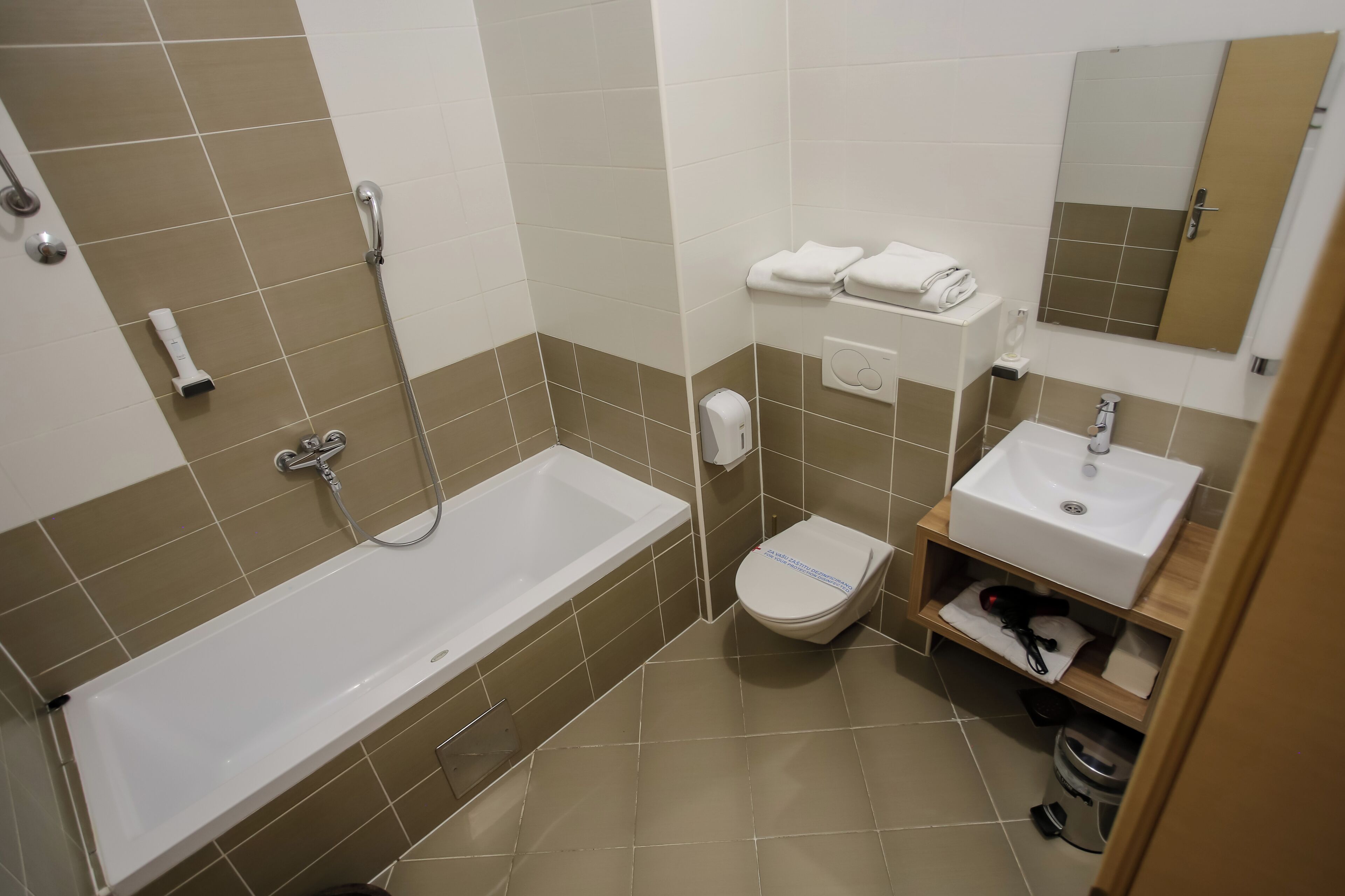 A bathroom with a bathtub, toilet, sink, and a mirror.