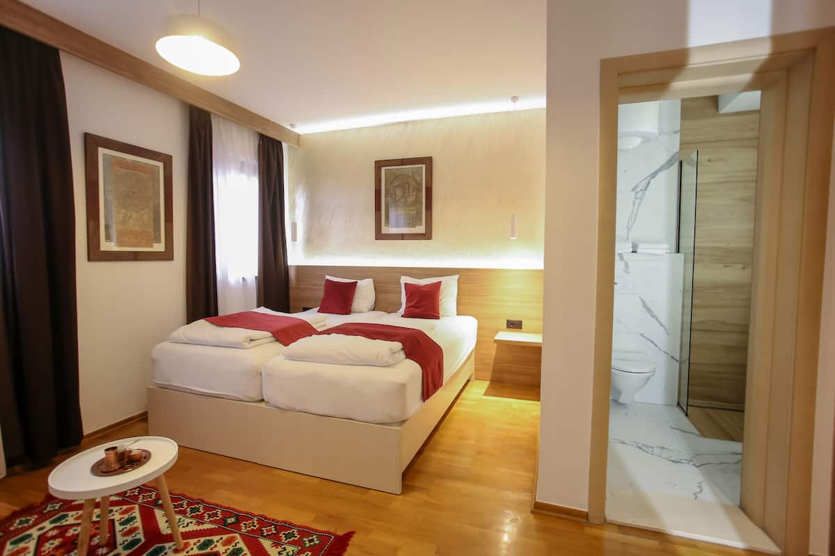 Un dormitorio moderno con una cama grande, una mesita pequeña y una zona de ducha.