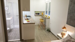 Uma cozinha moderna com micro-ondas, banquetas de bar e uma janela.