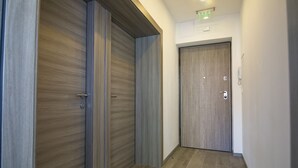 Um corredor com portas de madeira e piso de azulejos.