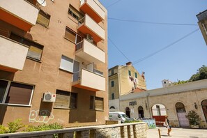 Un edificio de varios pisos con balcones, unidades de aire acondicionado y grafitis.