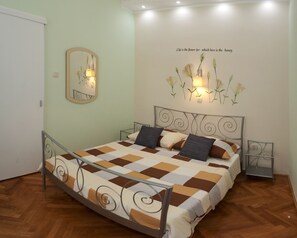 Un dormitorio con cama, espejo y una lámpara floral en la pared.
