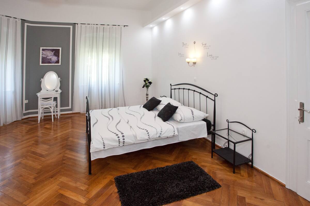 A bedroom with a bed, a chair, a desk, a mirror, and a wall with motivational quotes.