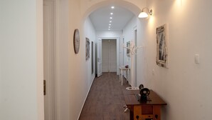 Um corredor com piso de madeira, paredes brancas e uma mesa de madeira com uma máquina de costura.