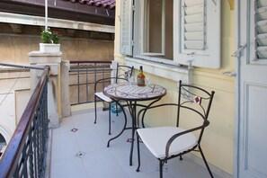 A balcony with a round table and two chairs, a potted plant, and a bottle of liquor. - Villa Barbara (Split)