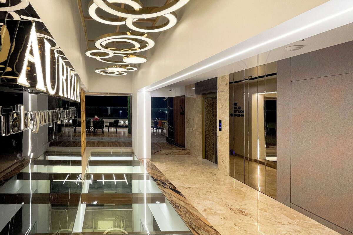 Un interior moderno con piso de vidrio, un candelabro central y un letrero que dice 'AURIA'.