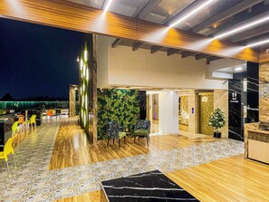 A modern lounge area with a wooden floor, patterned rugs, and a green wall with plants. - Hotel Auris & Banquets, Mumbai International Airport (Mumbai)
