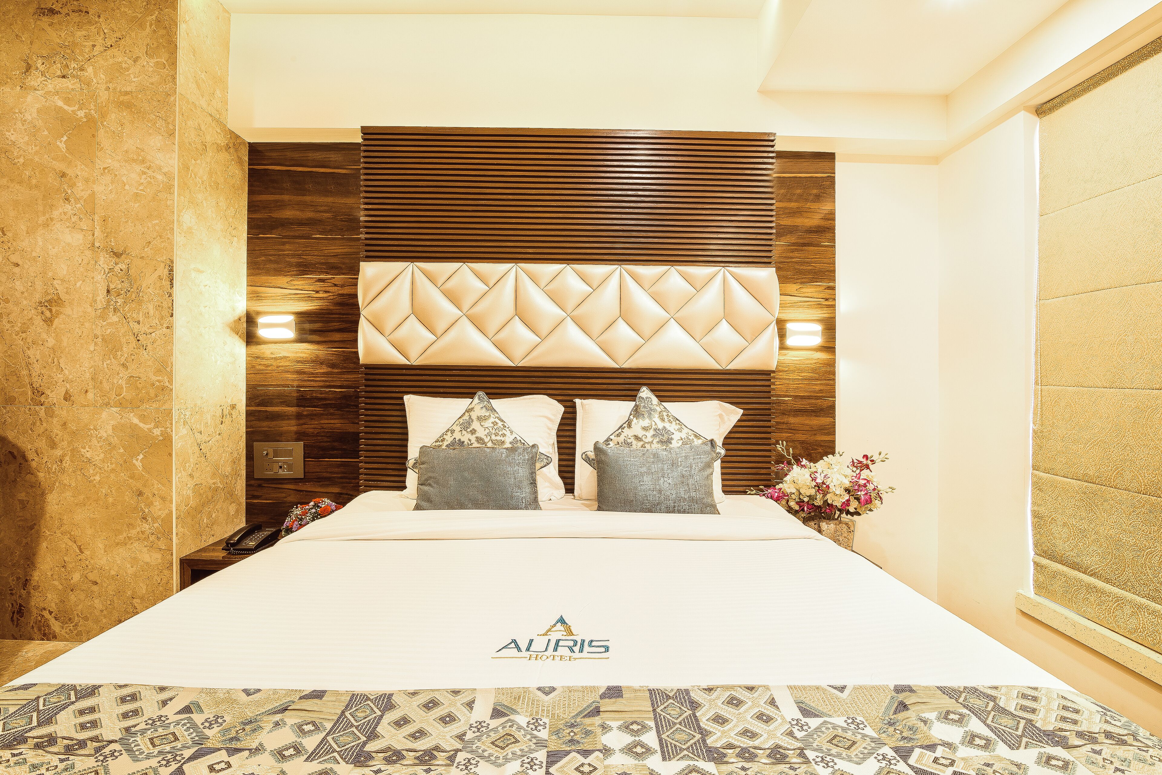Una habitación de hotel con una cama grande, cabecera de madera y colcha estampada.