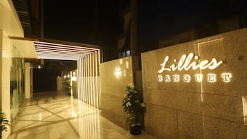 Una entrada bien iluminada con un diseño moderno, que presenta un letrero de neón que dice "Lillies Banquet".