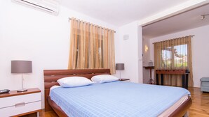 A bedroom with a wooden bed, white nightstands, and a window with curtains. - Cozy Villa in Okrug Gornij with swimming pool and all what is needed (Okrug Gornji)