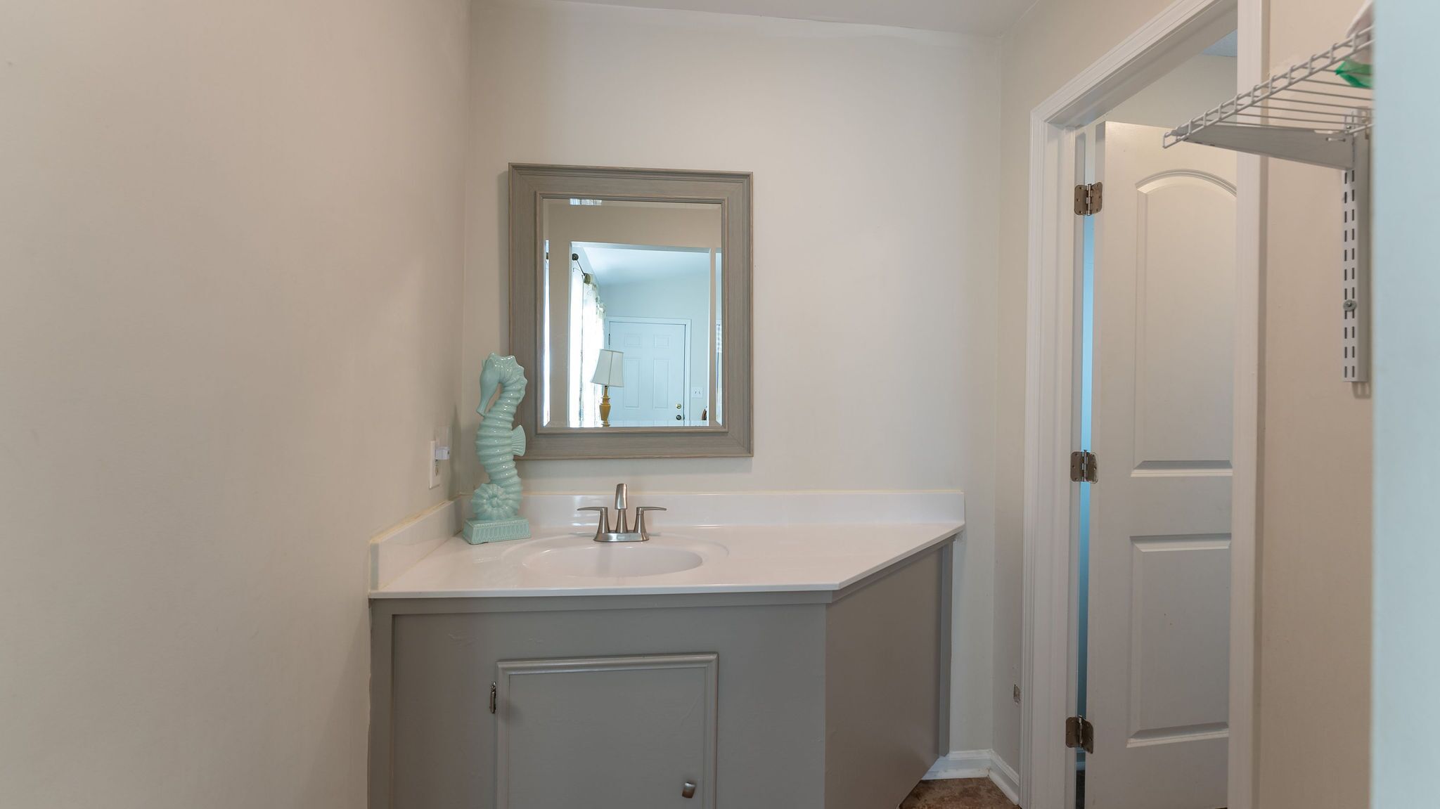 A bathroom with a white vanity, a mirror, and a seahorse decoration.