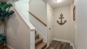 A staircase with wooden steps and a white handrail, leading to a door.