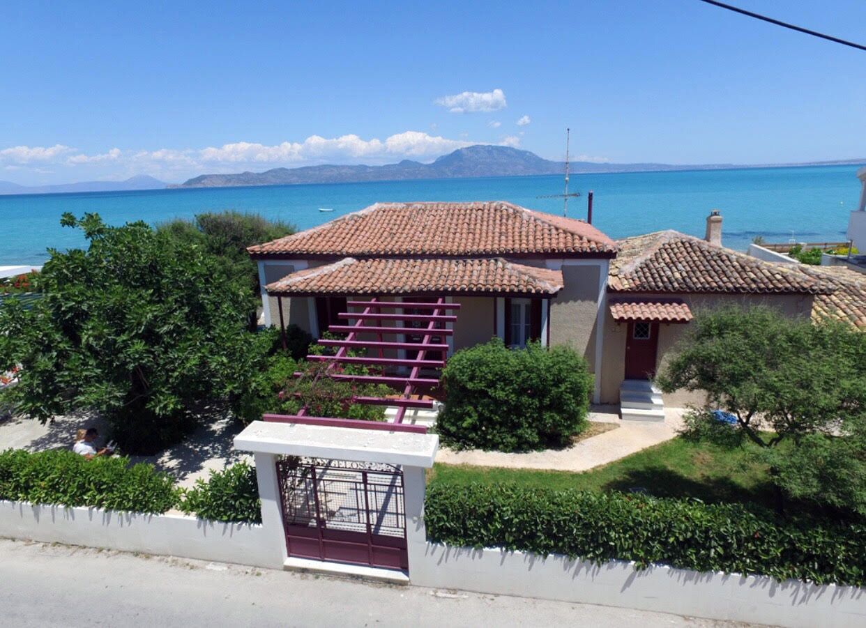 A coastal house with a tiled roof, a small garden, and a view of the sea.