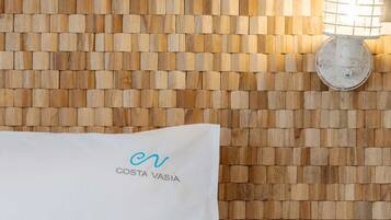 A wall with a woven pattern and a towel with 'COSTA VASIA' text.
