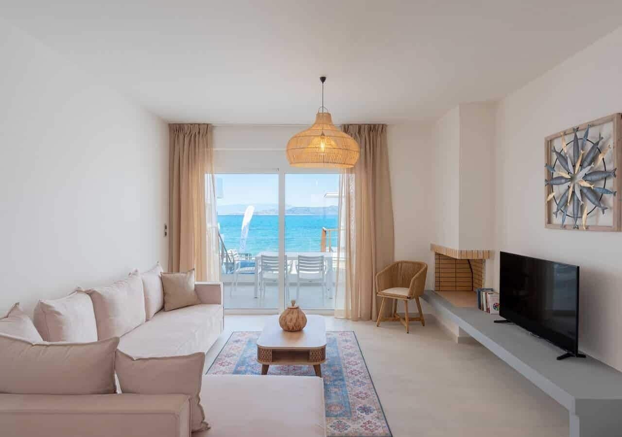 A modern living room with a sofa, a coffee table, a TV, and a view of the sea.