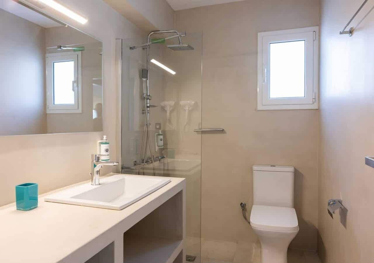 Une salle de bain moderne avec une douche à parois de verre, un lavabo blanc et des toilettes.