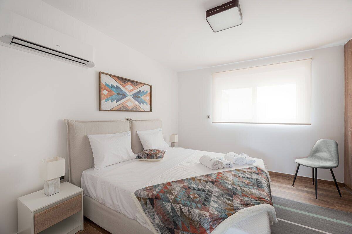 Una habitación de hotel con una cama, una mesita de noche, una silla y una ventana.